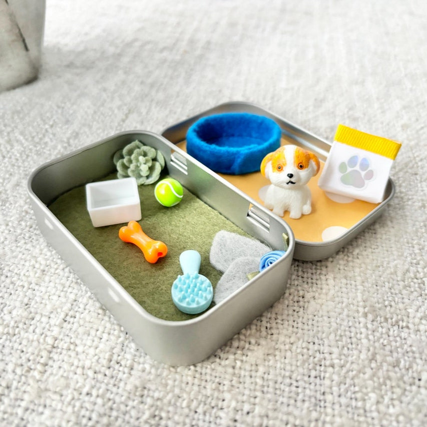 Pet toy set with various items including a small dog figure, balls, and a bowl on a textured surface.