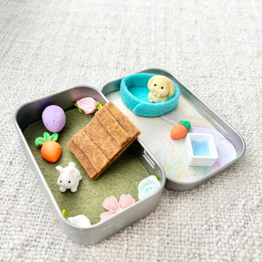 Playset with miniature furniture and toys inside a small container on a textured surface